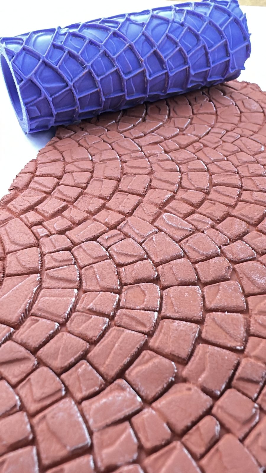 Cobblestone texture roller pressed into terracotta clay